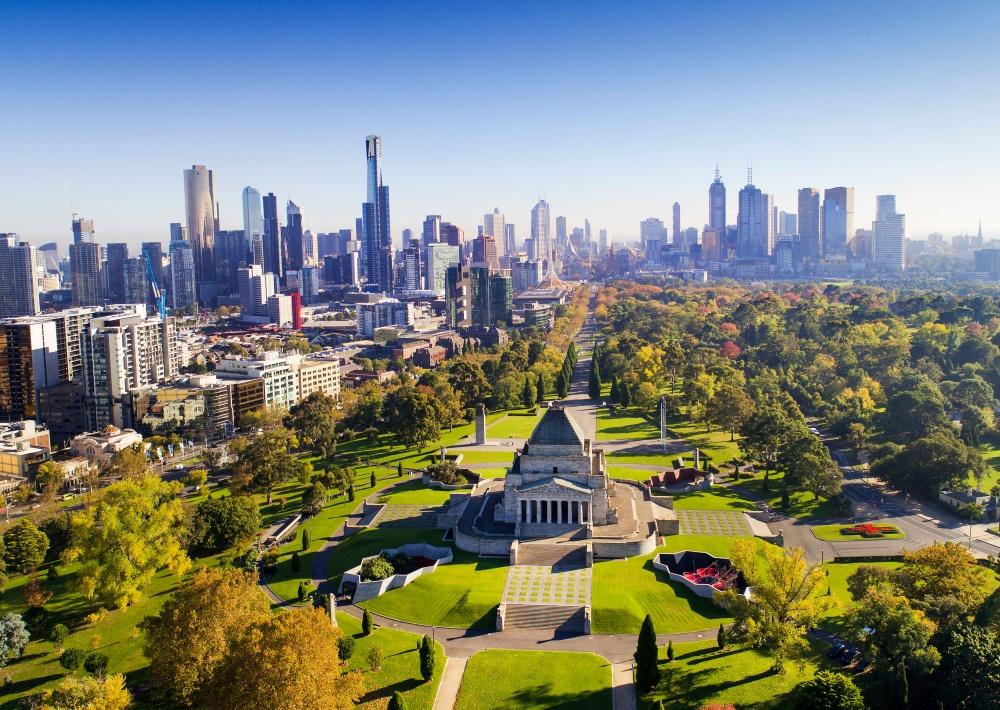 Birds-eye view over a shrine in the middle of a park and city skyline