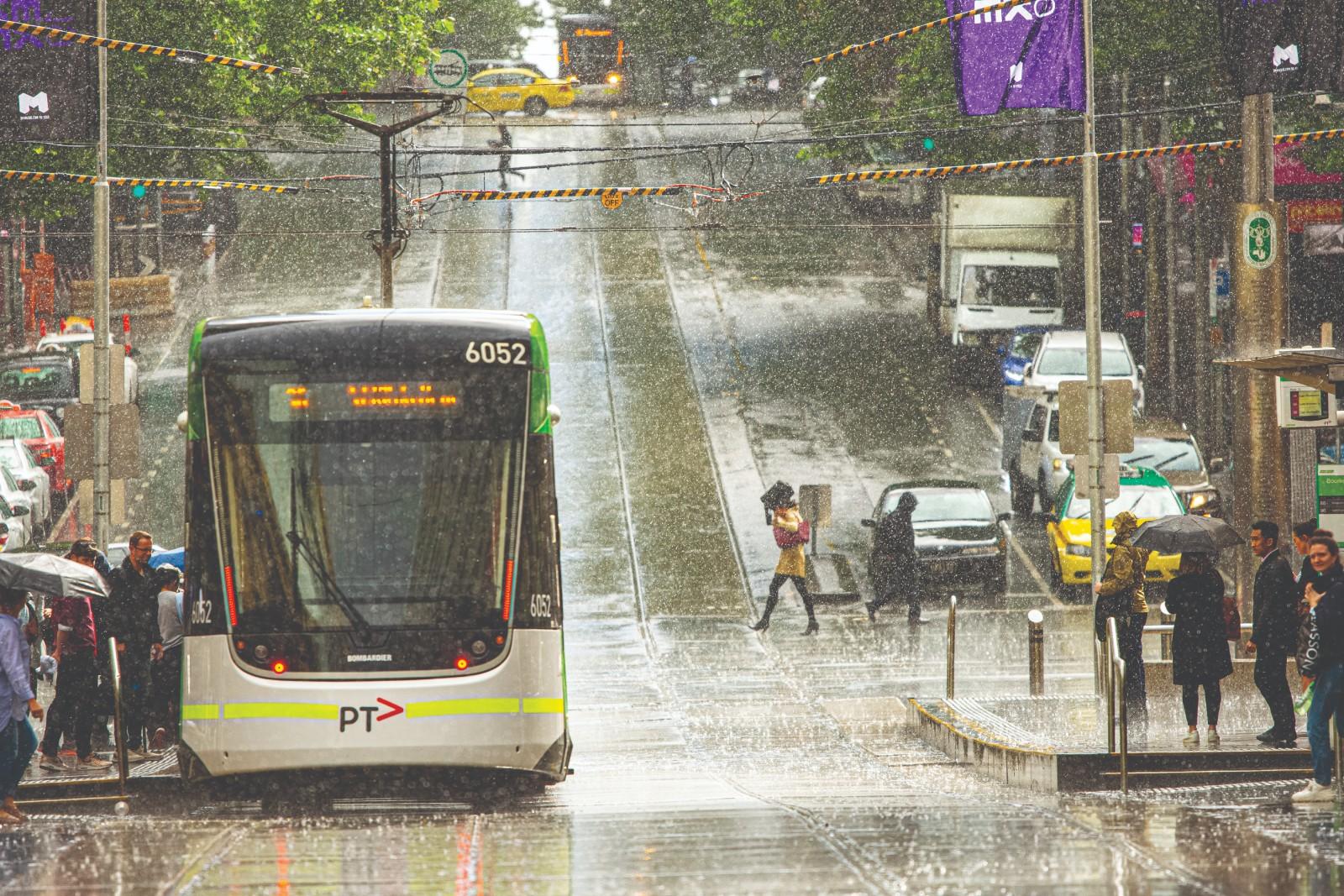 A tram and civilians in CBD on a rainy day