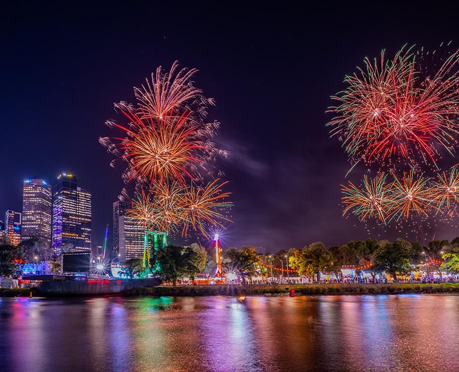 Colourful fireworks over the city, reflected in the Yarra River.