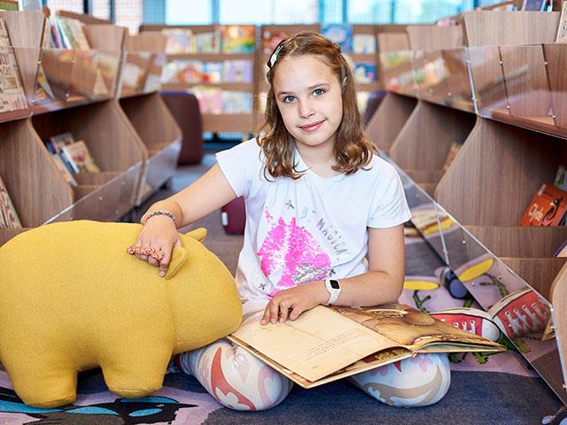 Child sitting on the floor of the library with books and toys.