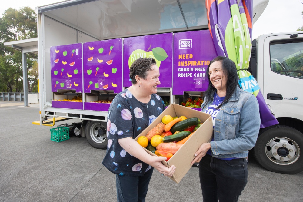 Lady passing box of produce over smiling community member