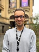 A person stands in front of Melbourne Town Hall.