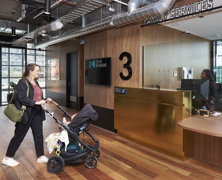 Person with pram walking up to a reception area in building.