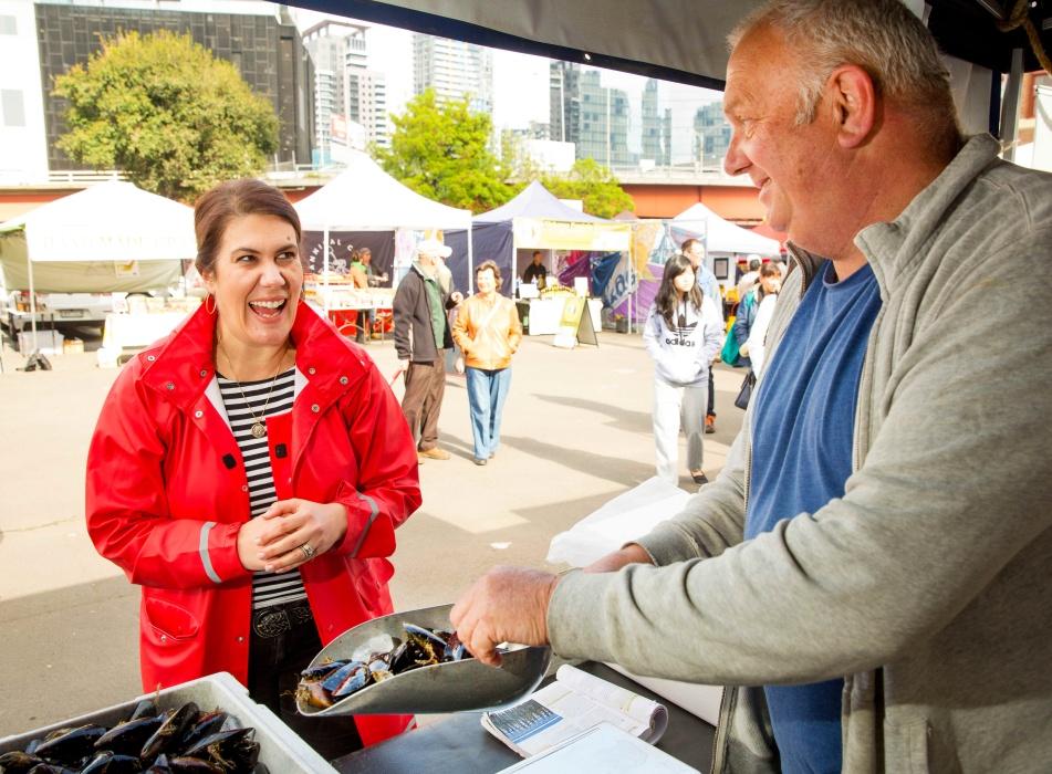 Man selling mussels to smiling woman at market