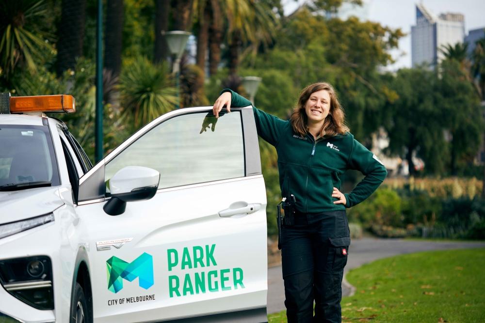 A woman standing next to maintenance car in a park