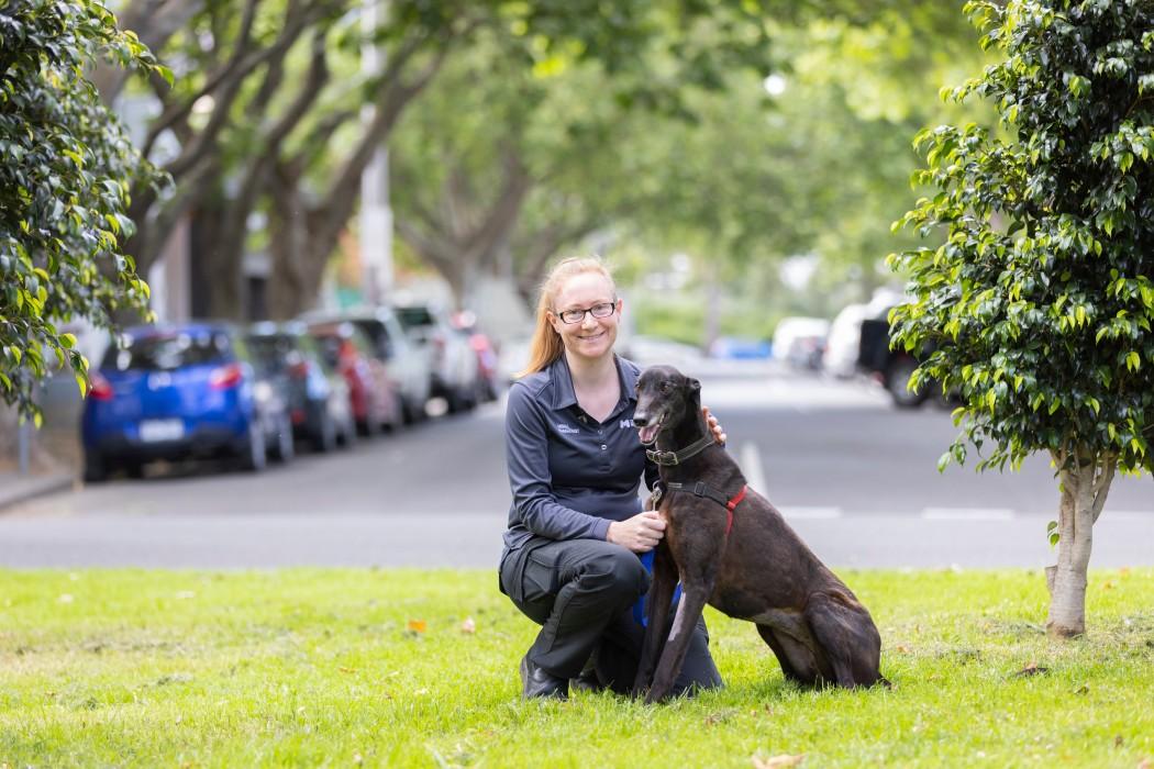 Person crouching with a dog, both smiling.
