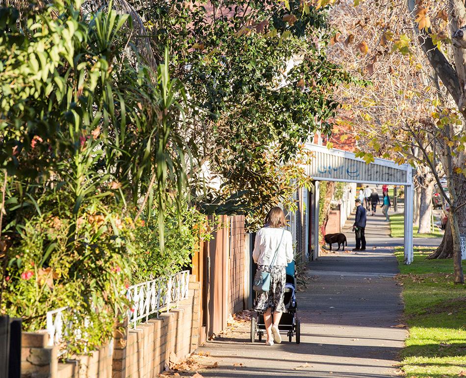  A person walking with a pram on a residential street.