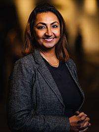 Smiling woman in grey jacket over black top.
