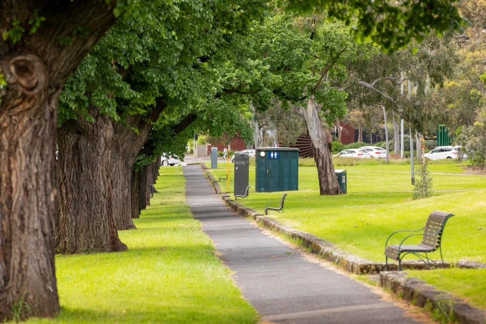 A path in a park with benches and a public toilet