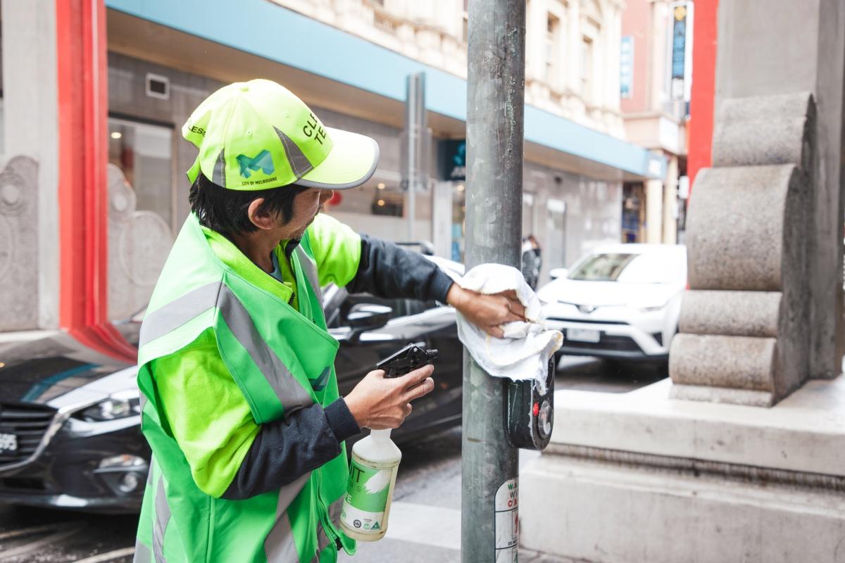 A street cleaner spraying and wiping a light post