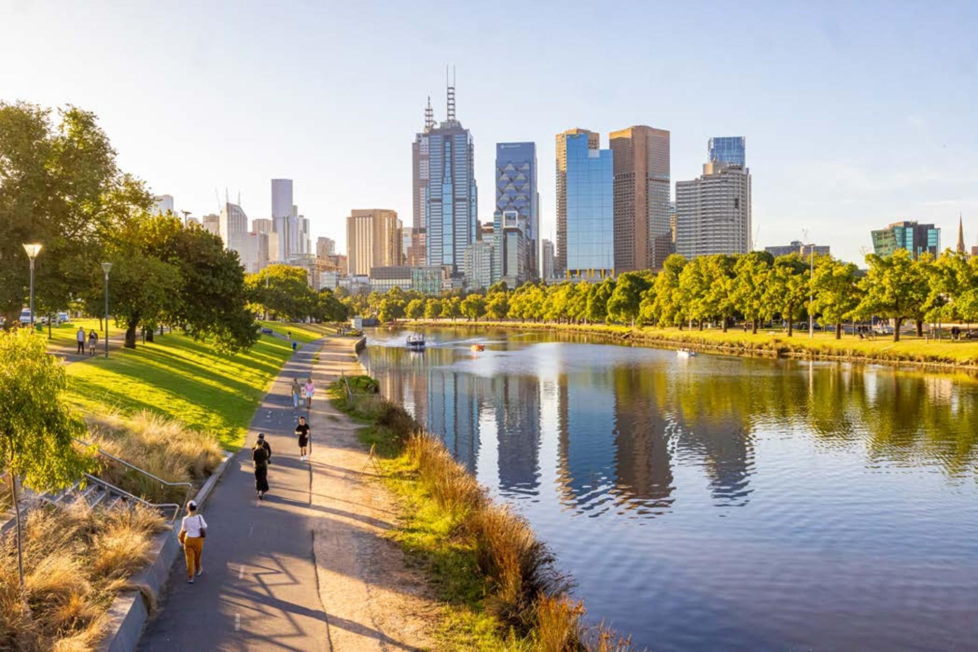 People walking along river path with skyline in the background