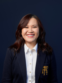 A person smiling at the camera. They are wearing formal clothes. 